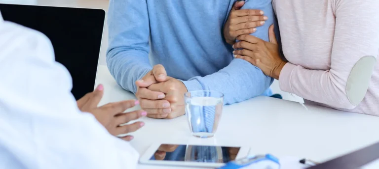Médecin spécialiste d'IRIFIV expliquant un protocole de fertilité personnalisé à un couple lors d'une consultation